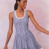 Blue gingham cotton mini dress with tank top straps, a tie detail at center front above a corset-inspired bodice that falls to a sweepy skirt.