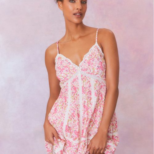 White mini dress with a pink floral pattern with lace insets and pintucking details, and features a smocked back, spaghetti straps, and an airy skirt finished with lace.