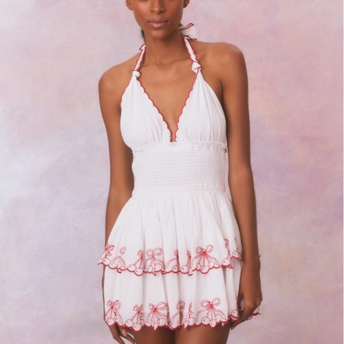 White organic cotton halter mini dress with a smocked bodice, and scalloped red cherry embroidery details on the tiers of the skirt and neckline.