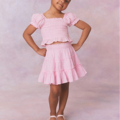 Pink gingham cotton off the shoulder top with puff sleeves and a smocked bodice flowing to a peplum finish for girls.