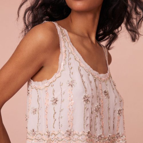 Swing crop top featuring embroidery and embellished beading all over in a zig zag pattern with stars. Has a subtle trim of chiffon around the neckline.