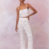 White cotton pointelle crochet floral flare pants with a self tie detail at center front on the double ribbed waistband.