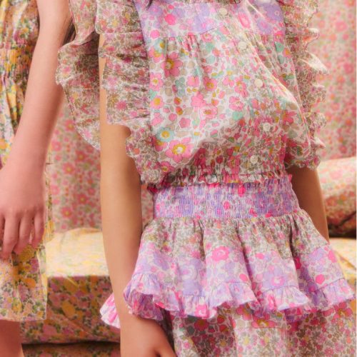 Girls' two-toned floral top with short flutter sleeves, a ruffled high neck, buttons down center front and a fixed waistline at the bottom hem.