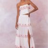 White cotton maxi skirt with red cherry embroideries on each tier of the skirt and the skirt includes an elastic waistband and a slit on the left leg that goes slightly above the knee.