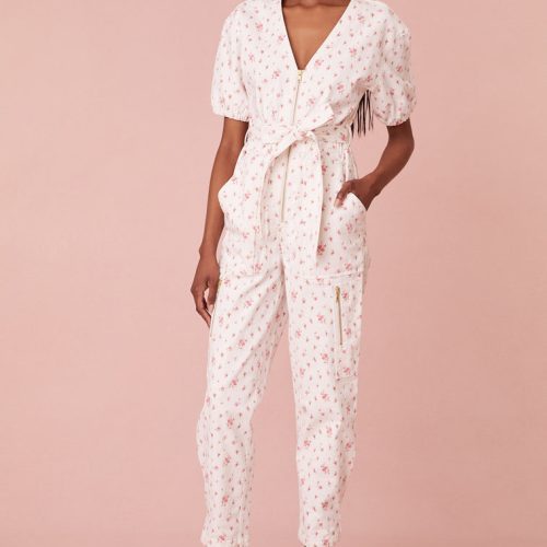 Jumpsuit featureing a slightly faded floral print on a stone-washed denim fabric. Features short puff sleeves, a v-neckline, cinching at the waist, elastic at the back, and a midi length. Includes a zipper at the front and a snap at the leg.