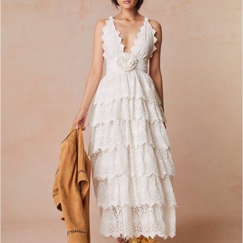 Lace maxi dress with a halter neckline outlined with a scallop edge that criss-crosses in the back. A fabric rosette adorns the center front before falling to the epic, multi-tiered skirt.