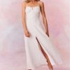 White maxi dress featuring thin spaghetti straps, bustier-inspired cups at the bust with shirring details, a playful keyhole cutout, a center front placket that stops at the hip above a center front slit.