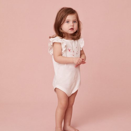 White onesie with ruffle shoulders and a floral embroidered bow stitched at front chest.