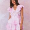 Pink hand-dyed cotton dress with lace embroidery details. Dress has a deep v neckline with ruffles on the outer edges of the shoulder and the bodice has an elastic waist and two flounced tiers.